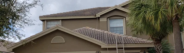 Two-story home before: dull, stained roof