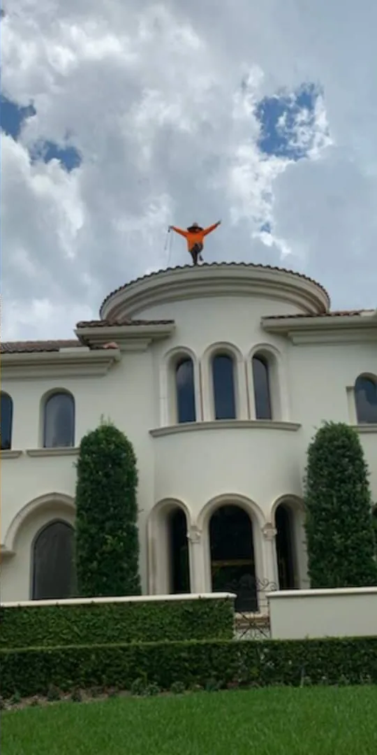 A Magic Touch crew member on the roof of a large estate home