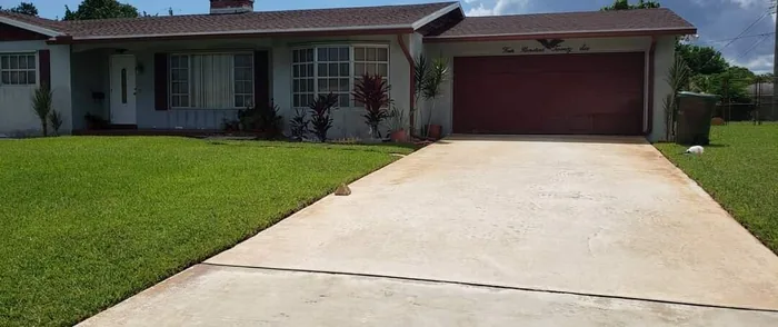 A long concrete driveway, clean, in front of a ranch home