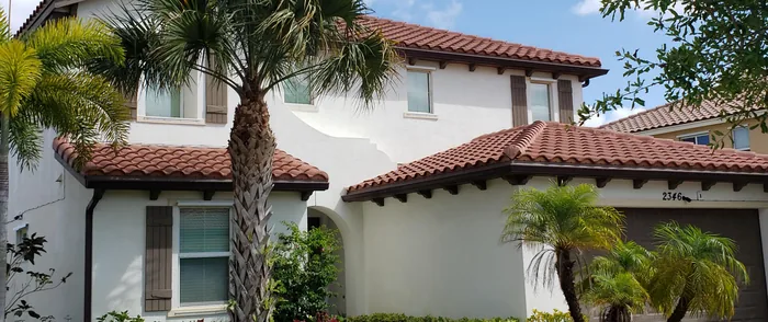 A white stucco home with a red tile roof after a house wash