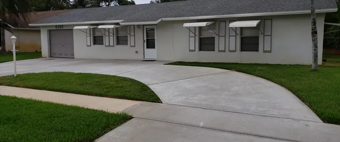 A ranch home with a clean driveway and sidewalk
